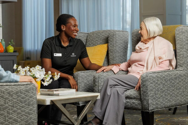 Image of elderly woman with Seasons employee smiling on a chair